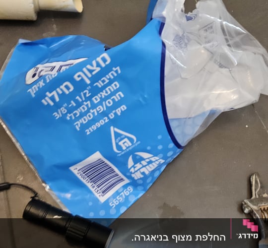 כלי עבודה של אינסטלטור על הרצפה, כולל פנס ומברג.